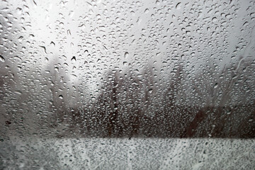 View on winter city and trees through wet windshield with rain drops.