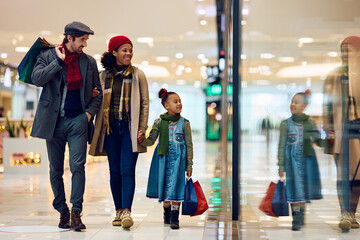 Happy multiracial family enjoys in Christmas shopping at mall.