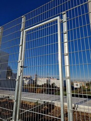 Fototapeta na wymiar strong galvanized welded mesh fencing is used around industrial halls and logistics centers and airports. gate with handle and lock. durable and cheap parts can be quickly built anywhere
