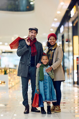 Happy multiracial family at shopping mall on Christmas looking at camera.