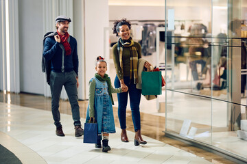 Happy multiracial family walking through shopping mall.