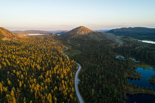 Aerial high angle view of river and road running through forest and mountainous landscape in northern Sweden