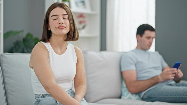Beautiful couple sitting on sofa silent with problem using smartphone at home