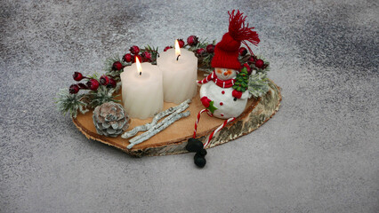 Advents und Weihnachtsdekoration: Kerzen, Zweige und lustiger Schneemann auf einer Baumscheibe...