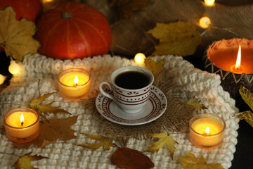 cup of coffee on the autumn background with leaves and candles