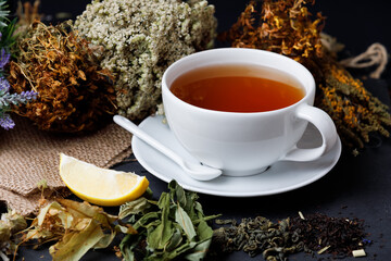 A cup of healthy tea with herbs and lemon on black background. Side view.