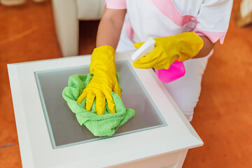 Close up image of  hotel maid cleaning table in a room.