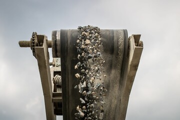 A photograph of the heavy machinery at the quarry, rocks and sand conveyor belt.