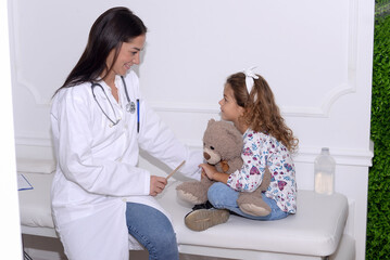Pediatrician examining little child patient’s throat at clinic