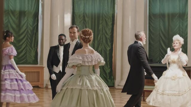 Full length shot of multiracial people in charming Victorian style dresses dancing with each other at glamorous debutante ball