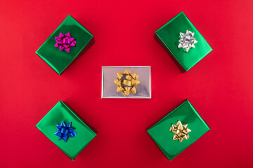 Don't delay, begin your holiday shopping adventure now. Top view shot of presents, holiday decor, sparkles on red background with marketing space.