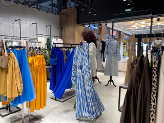 Shopping woman, women's fashion clothes in a store, boutique. Woman choosing clothes in a store