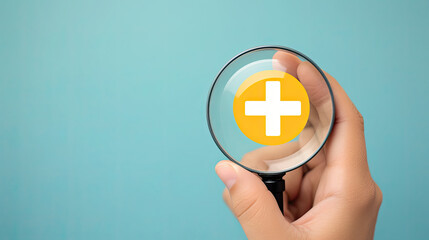 Obraz premium Hand holding magnifier glass with yellow plus sign symbol inside for focus healthcare insurance and offer positive thinking mindset of personal development concept. blue background
