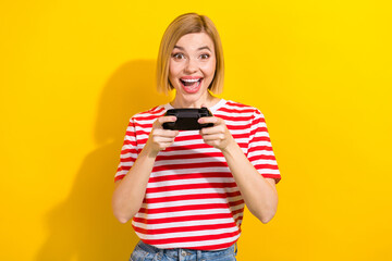 Portrait of impressed crazy girl wear stylish t-shirt hold playstation joystick play video game isolated on bright yellow background