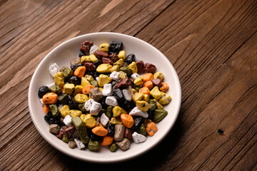 chocolate pebbles in a small ceramic dish. Chocolate candy in the form of small colorful pebbles. on wooden table. Coklat kerikil.  