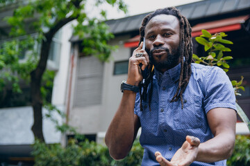 closeup of african man with dreadlocks outdoors, discussing talking on phone call