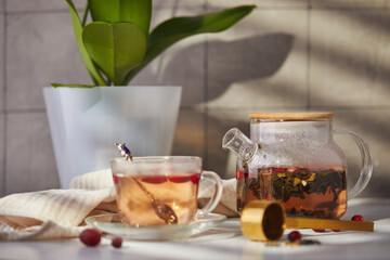 Fruits and berries tea. Glass teapot and cup on the table