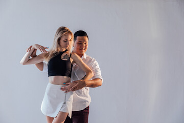 Man and woman dancers perform a dance on a white background in a studio