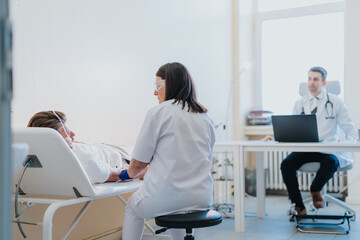 A doctor cares for a patient receiving infusion therapy. Medical records are checked in a hospital...