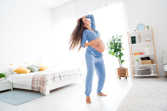 Photo of overjoyed glad cute pregnant girl with big tummy good mood free carefree time white interior indoors