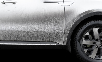 Side view of a very dirty car. Fragment of a dirty car. Dirty headlights, wheel and bumper of the...