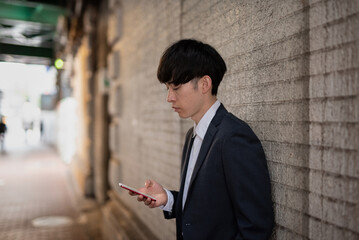 アーケードでスマホを見る若いビジネスマン