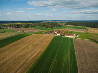 Drone image of rural landscape with different colored crops and forests. Bavaria, Germany