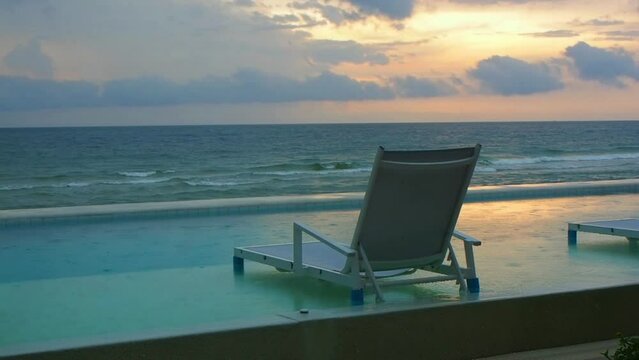 View of beach chair in swimming pool at the seaside villa in the morning light during dizzling.