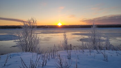 Sunrise over the frozen river in winter