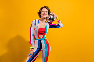Photo of toothy smiling confident clubber girl favorite weekend spending atmosphere bring disco ball isolated on yellow color background