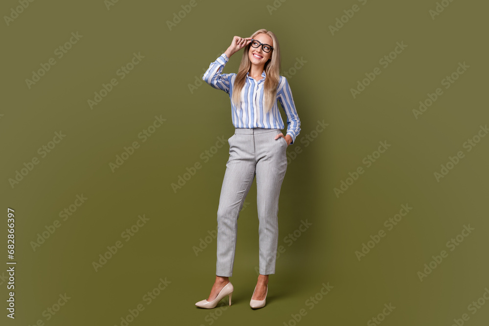 Sticker Full body photo of blonde lovely young lady touch specs look empty space dressed stylish striped garment isolated on khaki color background