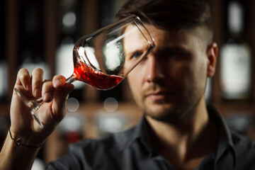Bokal of red wine on background, male sommelier appreciating drink