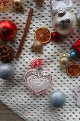 Various colorful Christmas ornaments, small presents and seasonal spices on white knitted blanket. Top view.