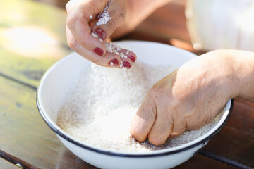 Woman's washing raw rice in the bowl - obrazy, fototapety, plakaty