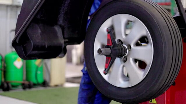Mechanic removes car tire and balancing wheels. 3d wheel alignment sensor placed on tires of car. wheel balancing in garage. Computer wheel alignment 