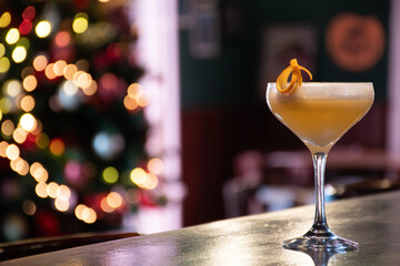 fancy pornstar martini glass with yellow cocktail lime orange peel garnish on pub counter