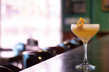 fancy glass with lemon orange peel garnish of yellow cocktail on pub counter porn star martini