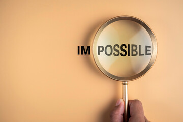 Magnifying glass in hanh focus on possible text and not focus impossible word. Believe in hope to...