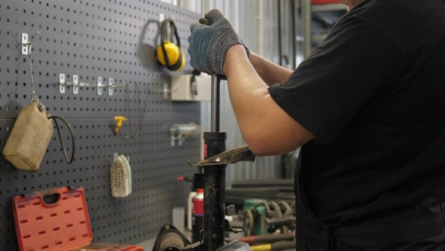 A close-up of a mechanic disassembling a shock absorber in an auto repair shop, repairing shock absorbers. Disassembly and repair of the car in a modern service station.
