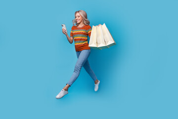 Full length photo of adorable sweet lady wear print shirt jumping virtual shopping modern device...