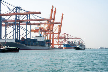 Obraz premium Big crane loading cargo container from truck to container ship in the international terminal logistic sea port concept freight shipping by ship, forwarder mast shipping