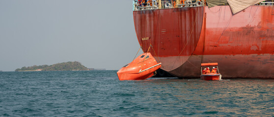 Watertight lifeboat test. Port state control. Lowering orange totally enclosed lifeboat to water....