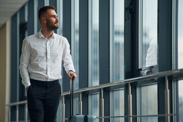 Standing, looking through the windows. Young handsome man in the airport
