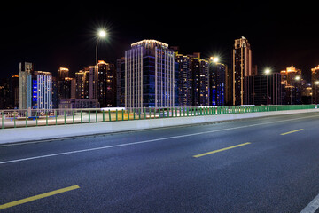 Asphalt highway road and urban buildings scenery at night