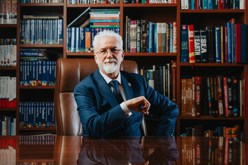 Experienced elderly rector poses confidently in a book-filled library, symbolizing successful...