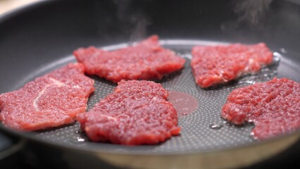 Dolly shot of Raw Steaks Cooking on Nonstick Pan.
