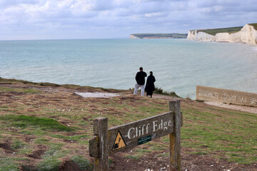 A warning sign Cliff Edge on the south coast of Britain. Series of 7 white chalk cliffs along the English Channel in South Downs National Park, United Kingdom.