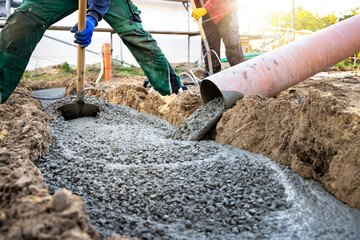 Construction worker spreading fresh concrete for a building foundation