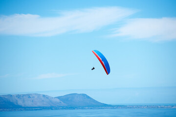 Pilot, parachute and paragliding in blue sky for flight, freedom and courage with extreme sport....