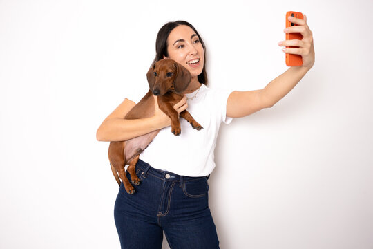 beautiful girl holding a small dog and make themselves self-portrait by phone